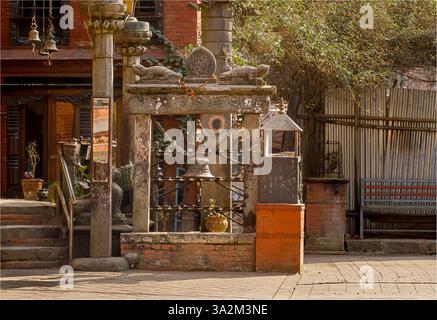 Bhaktapur, Nepal - 10. Februar 2025 - lokaler kleiner buddhistischer Tempel mit einer Glocke und einem Spiegel auf einem Pfosten Stockfoto
