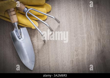 Edelstahl Handkelle Rechen gelbes Leder Sicherheitshandschuhe auf Holzplatte Kopierraum Bild Landwirtschaft Konzept Stockfoto