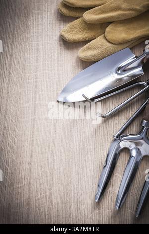 Stahl Gartenkelle Gabel Handspatrechen und Leder Sicherheitshandschuhe auf Holzbrett Landwirtschaftskonzept Stockfoto