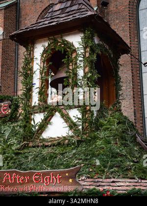 Der Turm eines Weihnachtsmarkthauses mit einer Glocke im Inneren und verziert mit Tannenzweigen Stockfoto