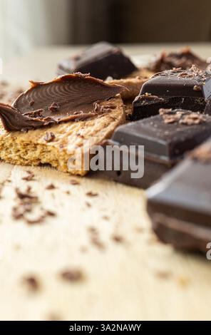 Makrodetail aus Schokoladenbrocken mit zerstoßenen Keksen und Kakaocreme. Rustikaler Holzhintergrund. Stockfoto