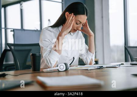 Kopfschmerzen haben. Ich fühle mich schlecht, überarbeitet. Geschäftsfrau ist drinnen im Büro. Stockfoto