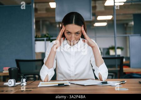 Kopfschmerzen haben. Ich fühle mich schlecht, überarbeitet. Geschäftsfrau ist drinnen im Büro. Stockfoto