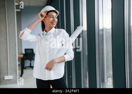 Architektin in Schutzhelm und weißer Kleidung ist drinnen. Stockfoto