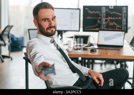 Viel Geld geben. In der Hand halten. Geschäftsmann sitzt am Computer und arbeitet im Büro. Stockfoto