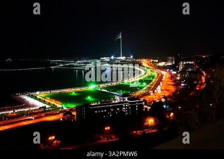 Abendlicher Blick auf Baku. Beleuchtete Skyline von Baku, Aserbaidschan bei Nacht mit Lichtern von Gebäuden, die sich im Wasser spiegeln. Stockfoto