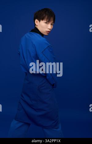 Selbstbewusster junger Mann in blauer Kleidung posiert künstlerisch vor einem lebendigen Hintergrund. Stockfoto