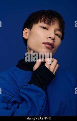 Ein junger, gutaussehender asiatischer Mann posiert elegant in einem leuchtend blauen Outfit. Stockfoto