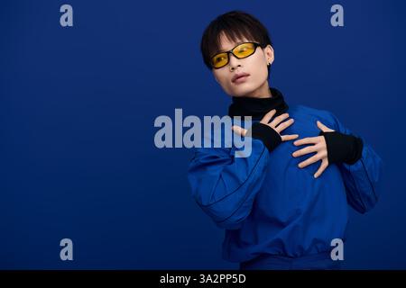Selbstbewusster junger Mann zeigt seinen Stil, der vor blauen Wänden posiert. Stockfoto