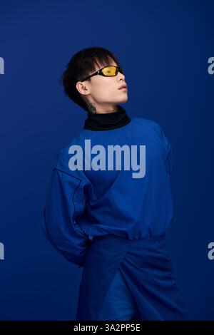 Selbstbewusster junger asiatischer Mann zeigt moderne Mode und posiert selbstbewusst in künstlerischer Umgebung. Stockfoto