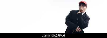 Selbstbewusster junger asiatischer Mann in trendiger Kleidung zeigt eine einzigartige Pose mit verspieltem Look. Stockfoto