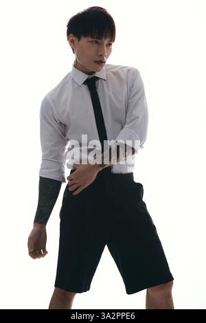 Ein junger, gutaussehender asiatischer Mann posiert selbstbewusst und zeigt seinen einzigartigen Stil und seine Tätowierkunst. Stockfoto