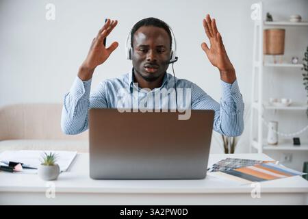 Misserfolg, mit erhobenen Händen, schockiert. Geschäftsmann arbeitet im Büro mit Laptop. Stockfoto