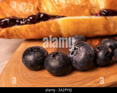 Extreme Nahaufnahme frischer Heidelbeeren und Croissants auf dem Schneidebrett Stockfoto