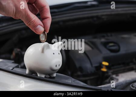 Sparkiste auf einem Auto mit geöffneter Motorhaube. Versicherungs- oder Kfz-Kostenkonzept. Stockfoto