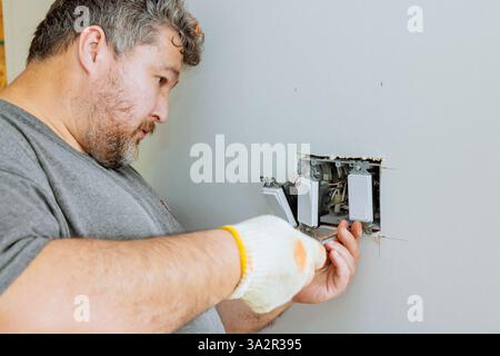 Ein Elektriker repariert Hausschalter während der Hausrenovierung Stockfoto