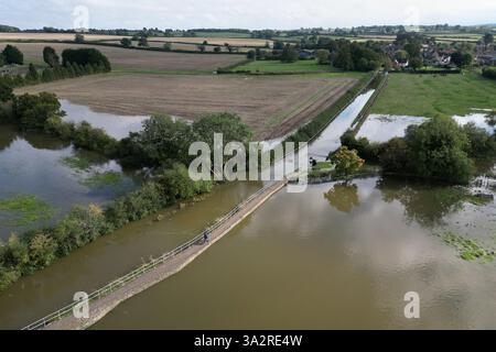 Die Leute laufen entlang der Carlton Road in Harrold, Bedfordshire, da sie nach dem Platzen des Flusses Great Ouse für Fahrzeuge gesperrt war. Für Donnerstag wurde eine gelbe Wetterwarnung für mehr starken Regen ausgegeben, als sich Großbritannien von Sturzfluten erholt, bei denen Häuser beschädigt und Reisen unterbrochen wurden. Bilddatum: Mittwoch, 25. September 2024. Stockfoto