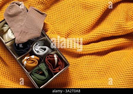 Organizer mit verschiedenen Socken auf orangefarbener Decke, Draufsicht. Leerzeichen für Text Stockfoto