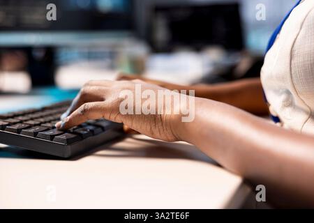Techniker tippen auf der Tastatur und konfigurieren die Serverfarm neu, um sie für die Datenverarbeitungsanforderungen der Kunden zu optimieren. Nahaufnahme eines Mitarbeiters, der am PC arbeitet, um sicherzustellen, dass das Rechenzentrum effizient funktioniert Stockfoto
