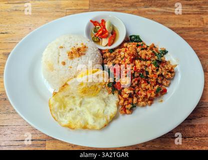 Würziges Basilikum gebratenes Huhn oder Pad Krapow Gai mit gedämpftem Reis und Spiegelei. Stockfoto