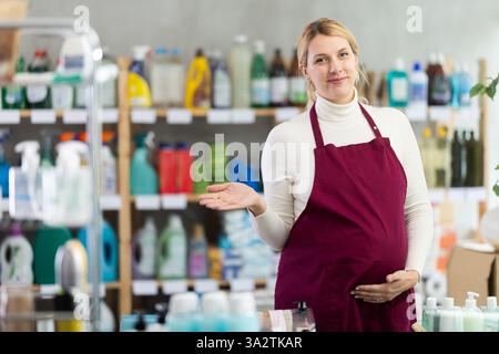 Schwangere Angestellte im Geschäft begrüßt Gäste mit einem Lächeln Stockfoto