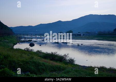 Gurye County, Südkorea - 3. Oktober 2021: Der Seomjin River fließt in der Abenddämmerung unter einer Brücke unter dem Himmel und reflektiert das verblassende Tageslicht. Die Umgebung Stockfoto