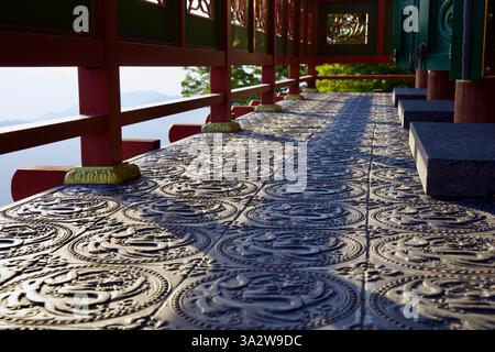Gurye County, Südkorea - 3. Oktober 2021: Die Sonne wirft lange Schatten über den verzierten Metallboden eines Tempelbalkons in der Saseongam Hermitage, fea Stockfoto