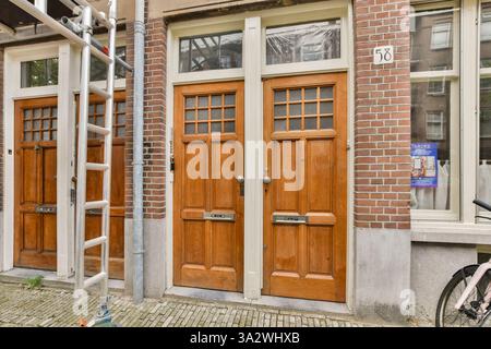 Das Bild zeigt zwei wunderschön gefertigte Vintage-Holztüren, die in einer urbanen Umgebung an einer Ziegelwand angebracht sind und architektonische Details und Texturen hervorheben. Stockfoto