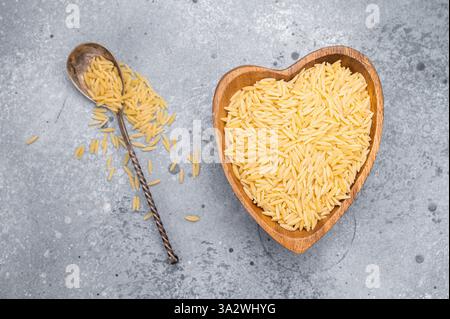 Rohe Orzo-Pasta, rohe trockene italienische Risoni in einer Schüssel. Grauer Hintergrund. Draufsicht. Stockfoto