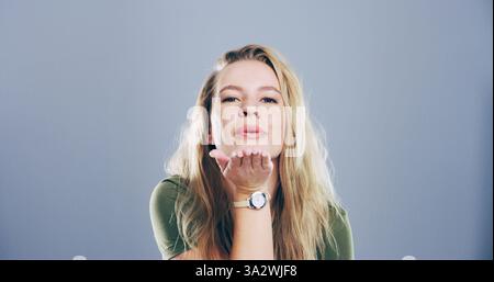 Flirten, Frauen und Blasen Kuss im Studio, Porträt und Geste für Romantik für Valentinstag oder Raum. Blauer Hintergrund, Modell und Person mit Stockfoto