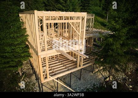 Die Drohne aus der Luft zeigt eine zweistöckige Wohnanlage mit Holzrahmen, die in der Nähe von Waldgebieten errichtet wird. Das Konzept des modernen ökologischen Bauens und der modernen Architektur. Stockfoto
