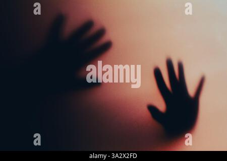 Künstlerische Darstellung von zwei Händen, die Schatten auf eine Wand werfen, wodurch ein abstrakter und dramatischer Effekt entsteht. Der subtile Verlauf im Hintergrund verbessert sich Stockfoto