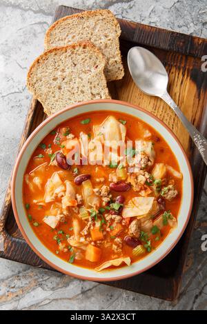 Gemahlene Rinderkohl-Suppe, mit roten Bohnen, Zwiebeln, Tomaten, Karotten und Sellerie aus der Nähe auf dem Teller auf dem Tisch. Vertikale Draufsicht von oben Stockfoto