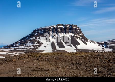 Vulkanische Felsformationen und schneebedeckte Klippen in Arnarfjordur, Westfjorden, Island. Stockfoto