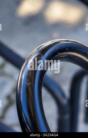 Eine Nahaufnahme eines schwarz lackierten Metallrohrstabs, der zu einem Halbkreis gebogen ist und eine abstrakte Form schafft Stockfoto