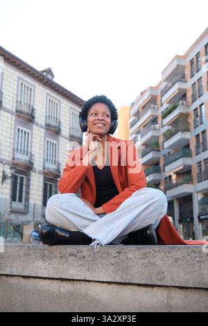 Junge Frau, die Musik in urbaner Umgebung genießt Stockfoto