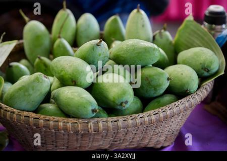 Nahaufnahme unreifer Mangos zum Verkauf im Bambuskorb Stockfoto