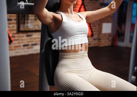 Frau, die auf der Brustpresse im Fitnessstudio trainiert Stockfoto