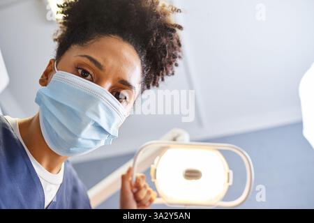 Zahnarzt in medizinischer Schutzmaske bei der Untersuchung in einer gut beleuchteten Klinik Stockfoto