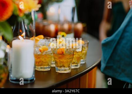 Gläser Whiskey mit Eis und Orangen auf einem Bartisch Stockfoto