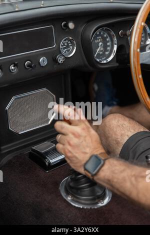 Die Hand des Mannes greift eine Oldtimer-Gangschaltung im Oldtimer-Interieur Stockfoto
