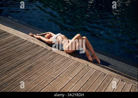 Draufsicht, Liegen. Frau in weißem Bikini ist in der Nähe des Schwimmbades. Stockfoto