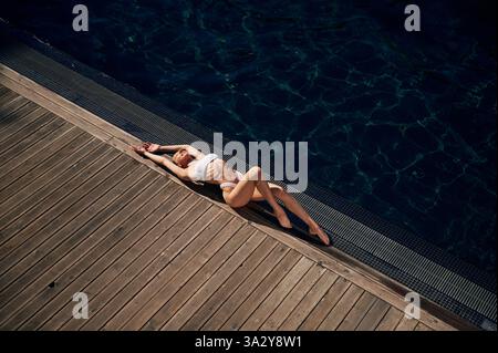 Draufsicht, Liegen. Frau in weißem Bikini ist in der Nähe des Schwimmbades. Stockfoto