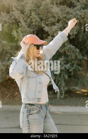 Eine fröhliche Frau hebt ihre Arme, um an einem sonnigen Tag im Freien zu feiern Stockfoto