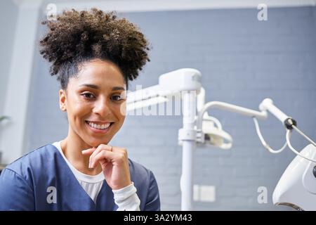 Lächelnder Zahnarzt posiert in einem modernen Klinikumfeld mit Geräten Stockfoto