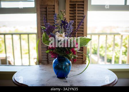 Lebendiger Wildblumenstrauß in blauer Glasvase Stockfoto
