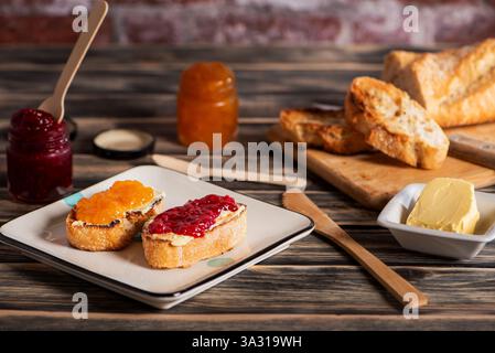 Toast mit Butter, Pfirsich- und Himbeermarmelade, zusammen mit allen Zutaten. Stockfoto