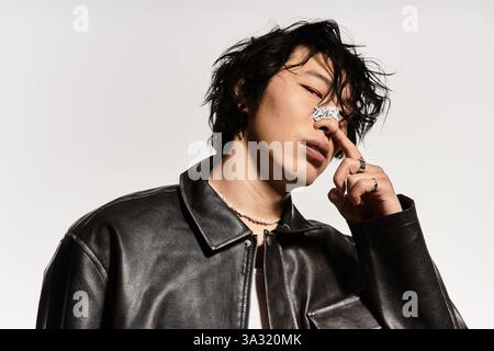 Stilvoller asiatischer Mann in Lederjacke und Nasenpflaster posiert im Studio. Stockfoto