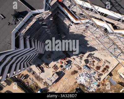 Auf der Baustelle werden in einem städtischen Gebiet unter hellem Sonnenlicht leuchtende Materialien und Geräte präsentiert. Draufsicht der Antenne Stockfoto