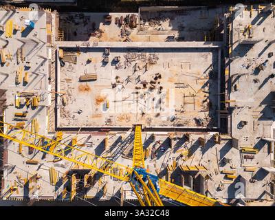 Auf der Baustelle werden in einem städtischen Gebiet unter hellem Sonnenlicht leuchtende Materialien und Geräte präsentiert. Draufsicht der Antenne Stockfoto